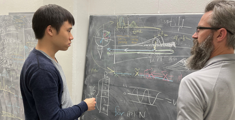 mentor and doctoral student discussing research at blackboard