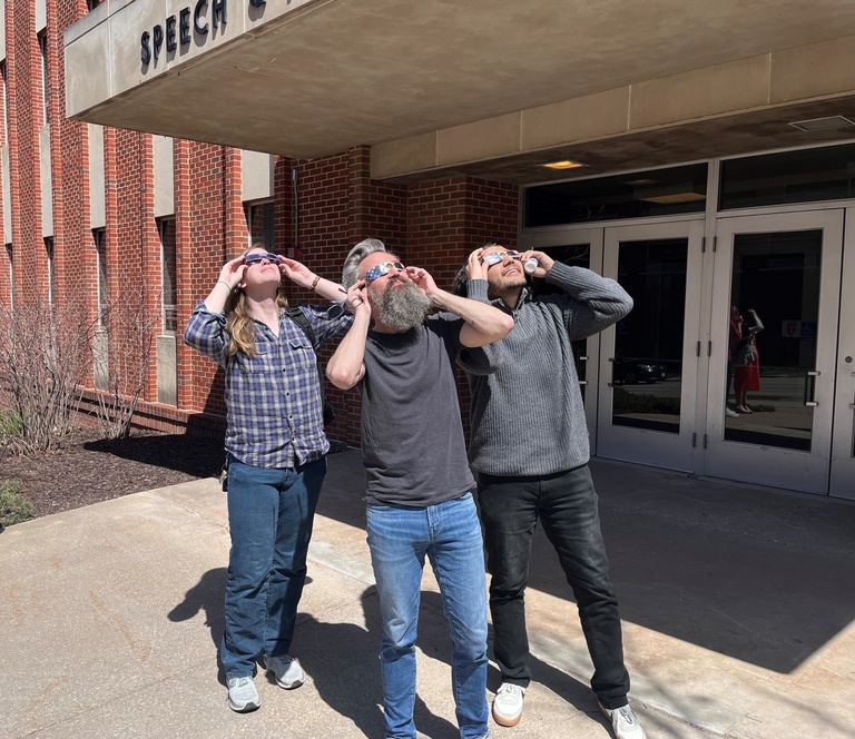 3 people looking at eclipse through glasses