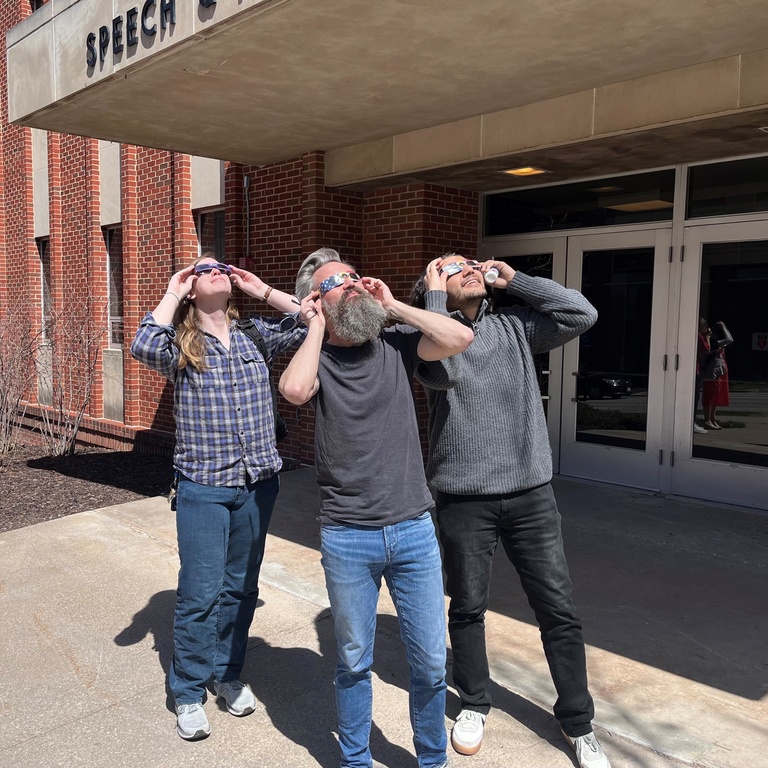 3 people looking at eclipse through glasses